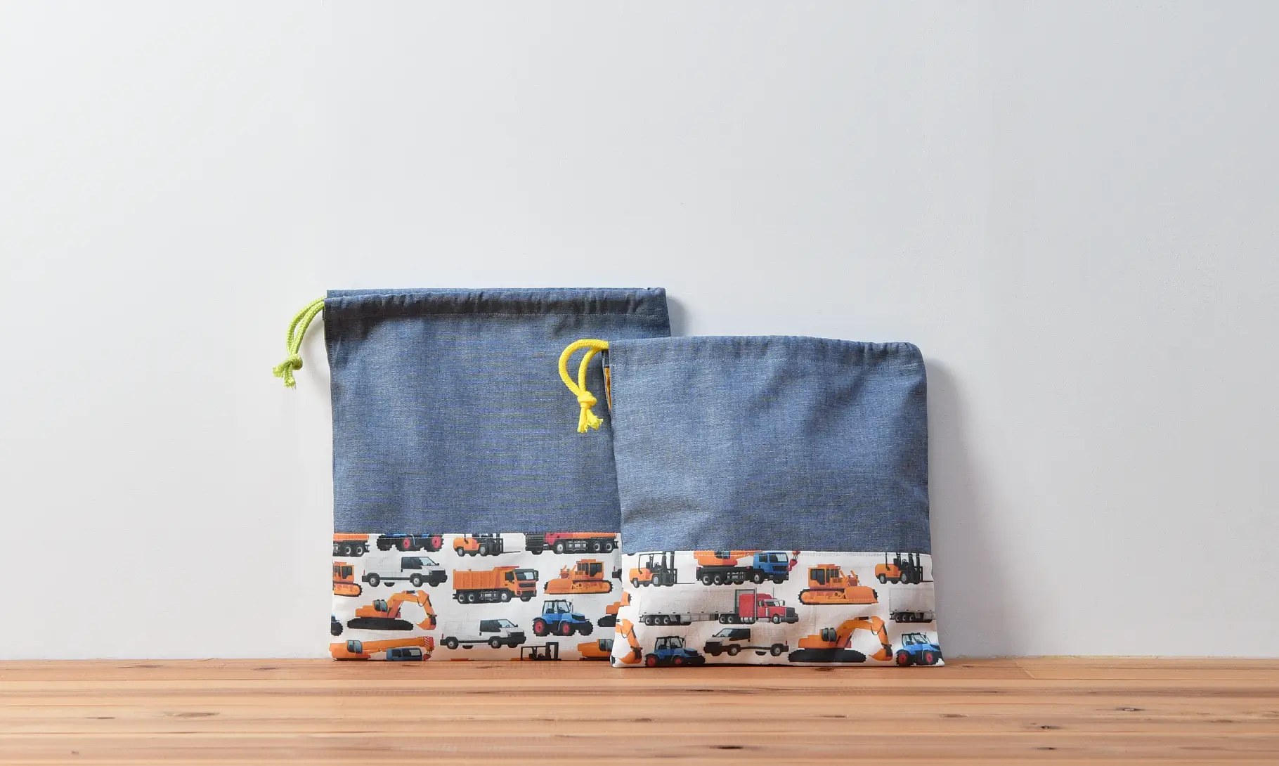 巾着袋(無地ダンガリー、車柄インザワールド働く車)ひもの色グリーンと、コップ袋(無地ダンガリー、車柄インザワールド働く車)ひもの色イエロー